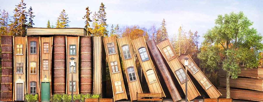 Holzhäuser in Buchform stehen aneinandergereiht vor einem Wald