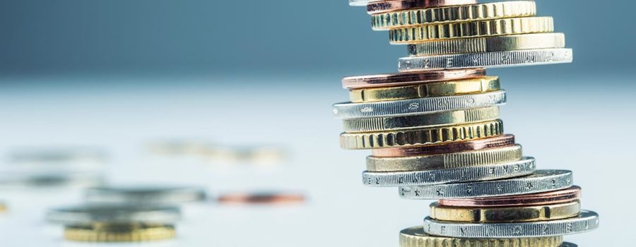 Ein Stapel Münzen vor einem blauen Hintergrund - Anschlussfinanzierung Immobilienkauf